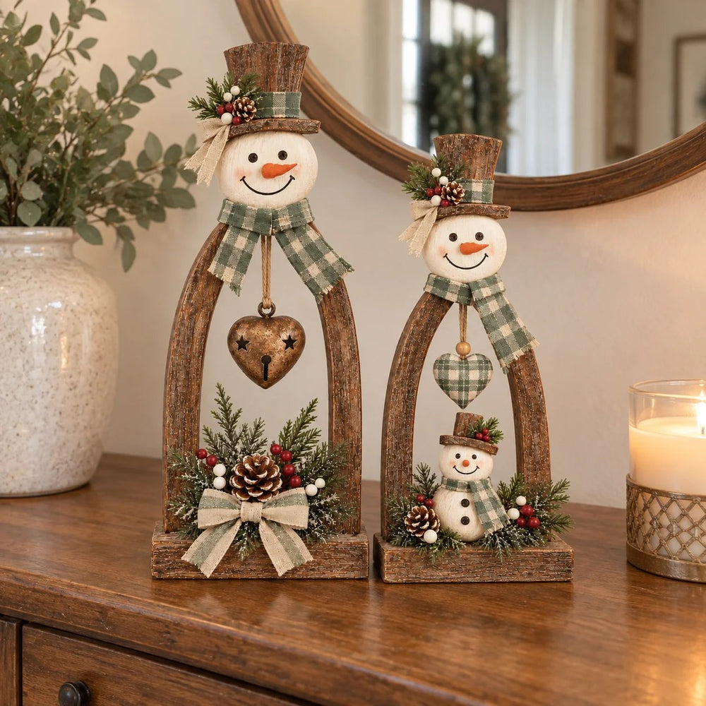 Tall and small rustic snowmen with sage plaid scarves, hanging hearts and decorative greenery on a wooden cabinet.